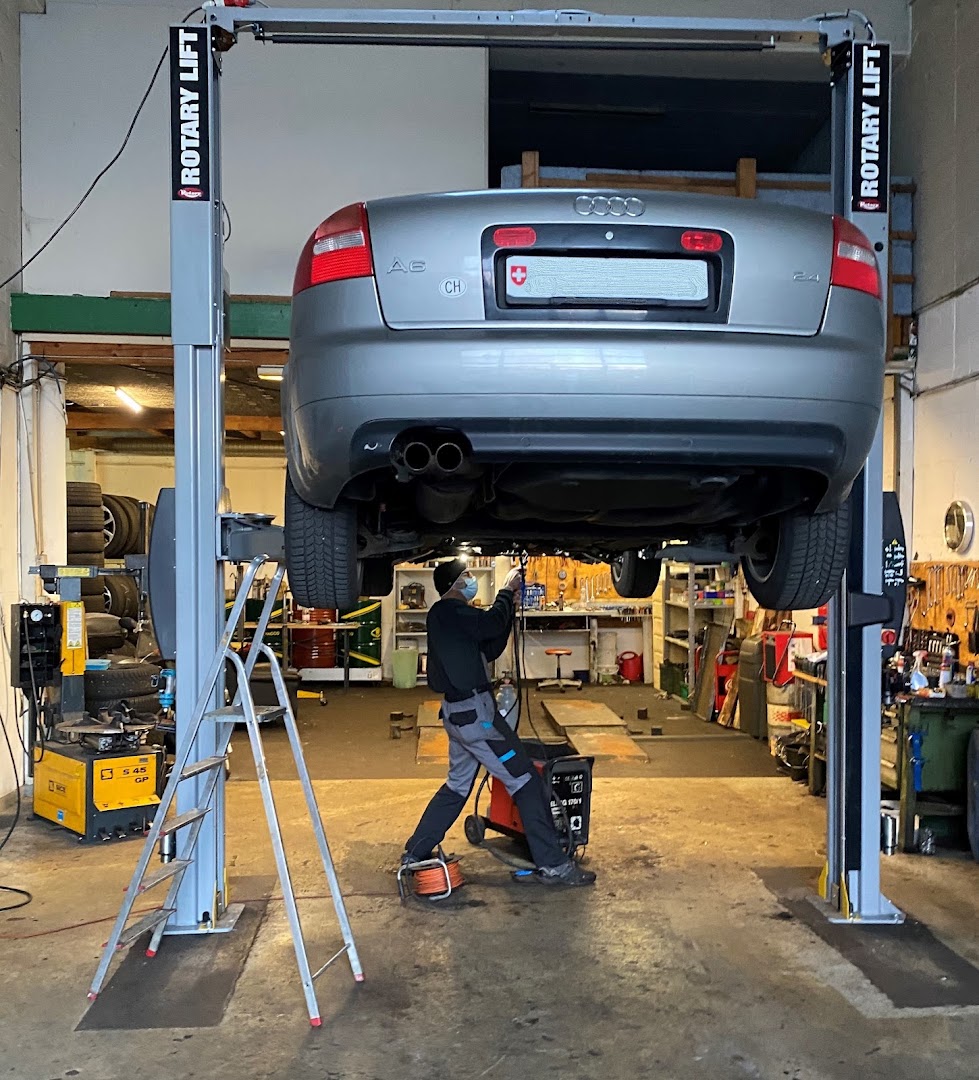 Mechaniker bei der Arbeit unter einem angehobenen Audi A6 in der Werkstatt der Veskovac Garage in Luzern